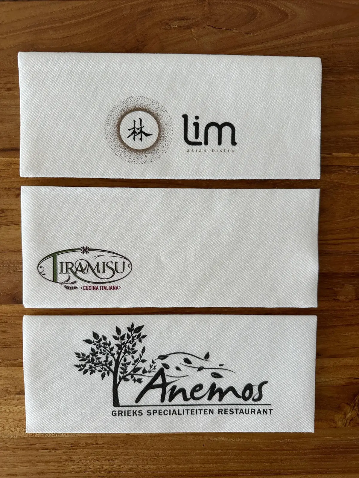 Drie bedrukte servetten in verschillende formaten met restaurantlogo